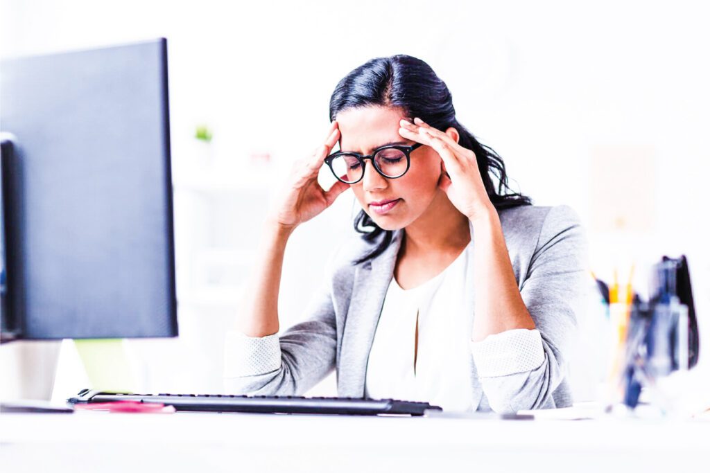 A lady uncomfortable in an office because there is too much glare coming through the window